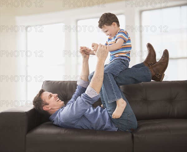 Caucasian father and son playing on sofa
