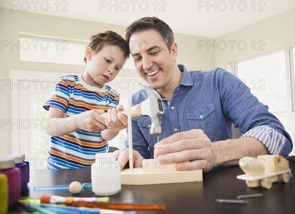 Caucasian father teaching son wood crafts