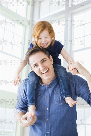 Caucasian father carrying daughter on shoulders