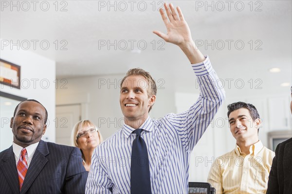 Businessman raising his hand in office