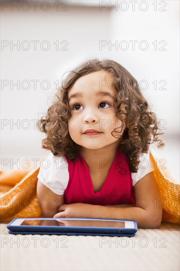 Mixed race girl using tablet computer on living room floor