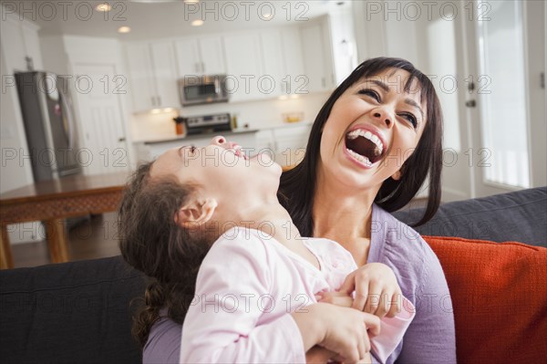 Mother and daughter playing on sofa