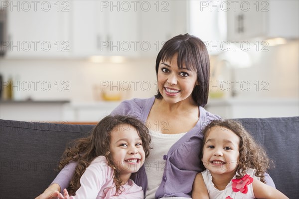 Mother and daughters smiling on sofa