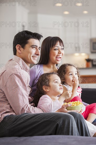 Family watching television together on sofa