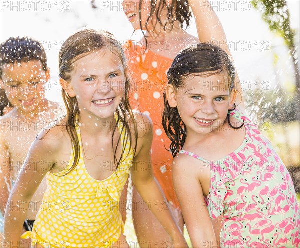 Caucasian children playing in sprinkler in backyard