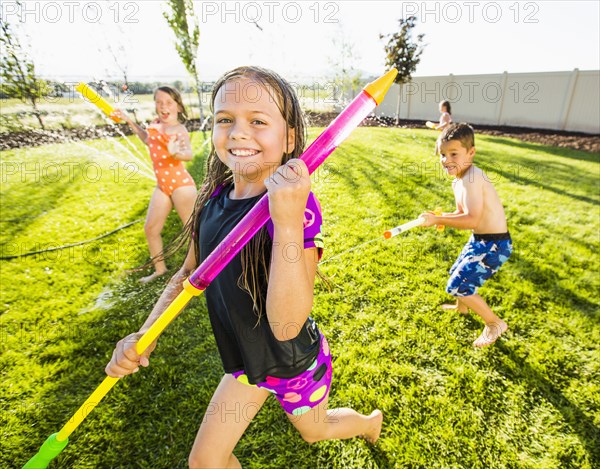 Caucasian children playing in sprinkler in backyard