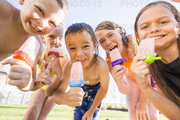 Caucasian children eating popsicles outdoors