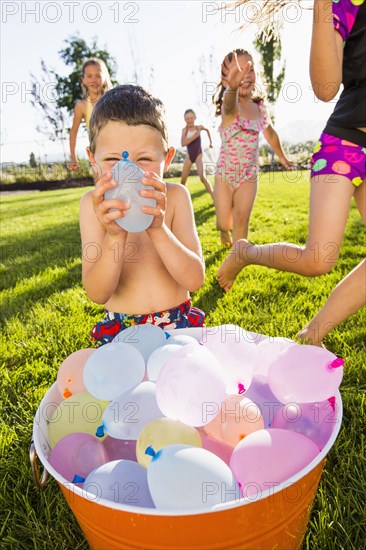 Caucasian children playing with water balloons in backyard