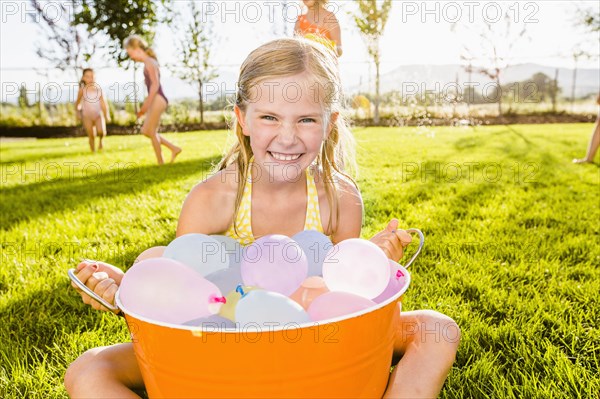 Caucasian girl playing with water balloons in backyard