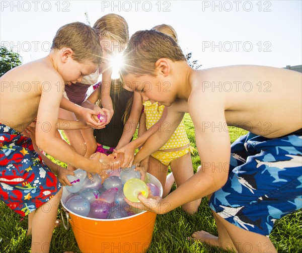 Caucasian children playing with water balloons in backyard