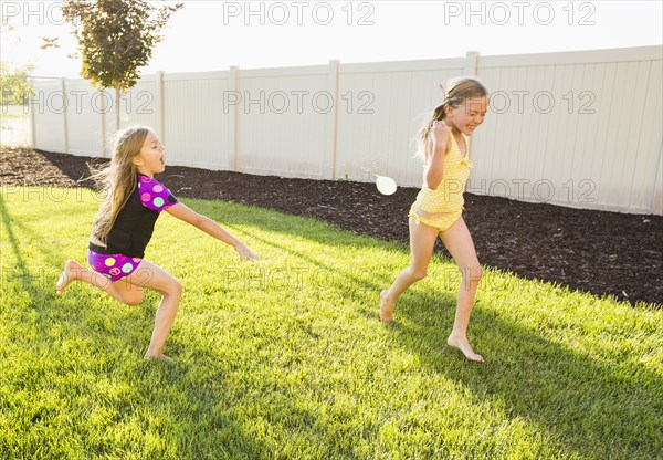 Caucasian girl throwing water balloons in backyard