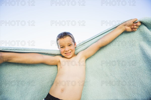 Caucasian boy playing with towel outdoors