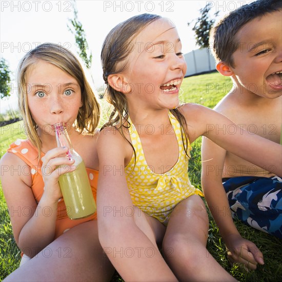 Caucasian children drinking soda in backyard