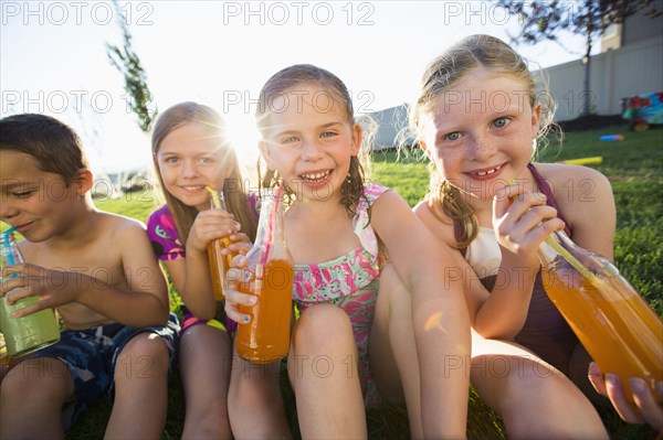 Caucasian children drinking soda in backyard