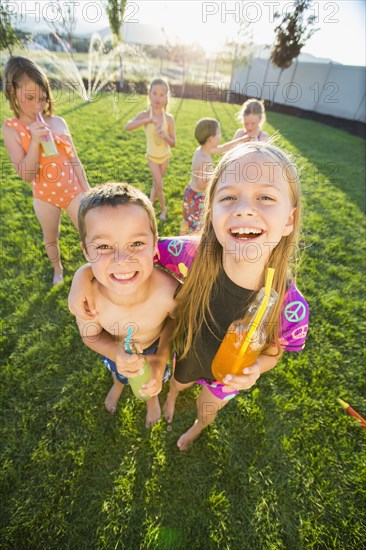 Caucasian children drinking soda in backyard