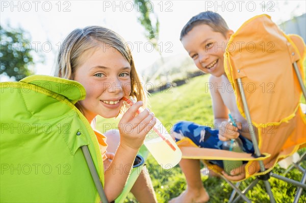 Caucasian children drinking soda in backyard