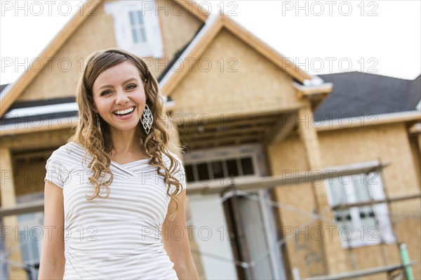 Caucasian woman smiling near house under construction
