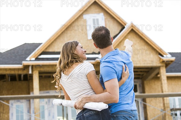 Caucasian couple admiring house under construction