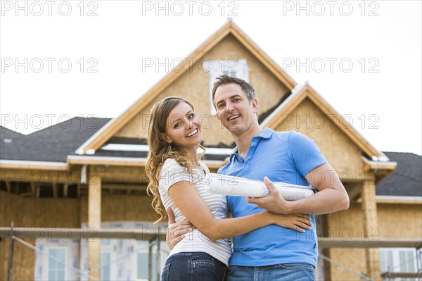 Caucasian couple hugging near house under construction