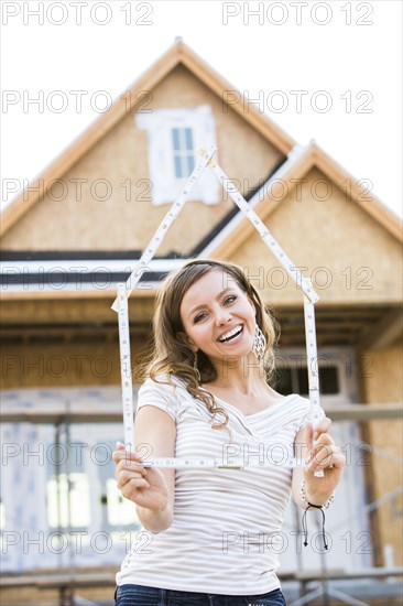 Caucasian woman holding frame near house under construction