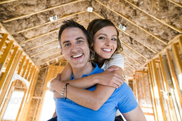 Caucasian couple hugging in house under construction