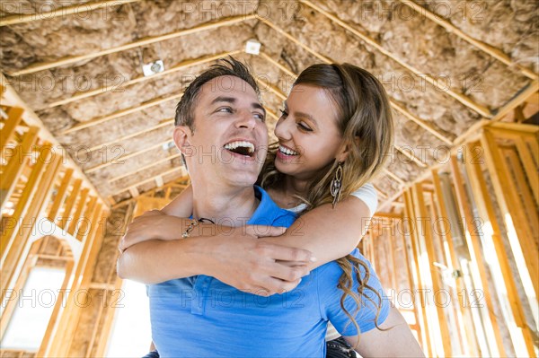 Caucasian couple hugging in house under construction