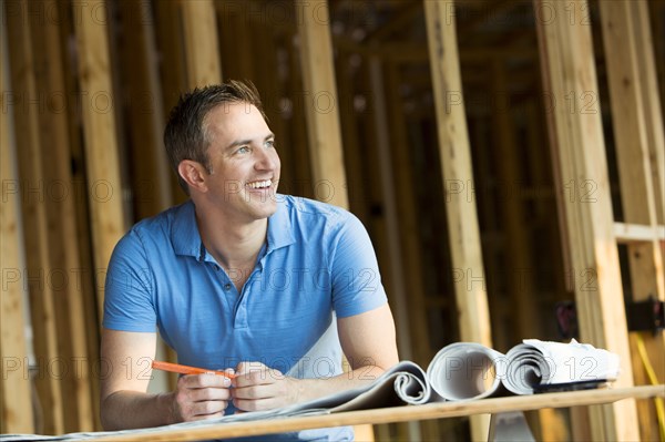 Caucasian man with blueprints in house under construction