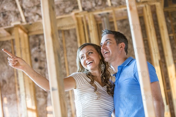 Caucasian couple admiring house under construction