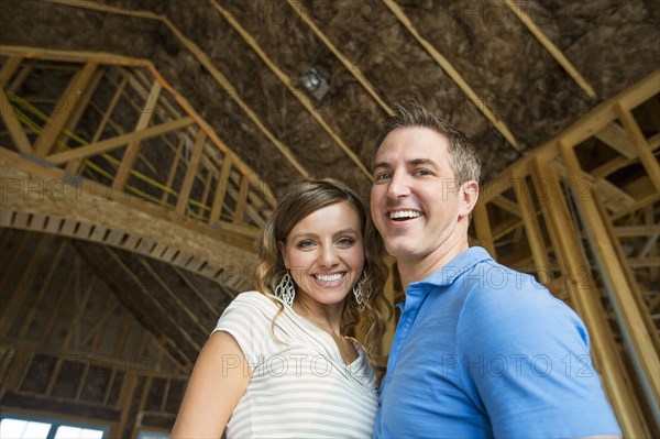 Caucasian couple hugging in house under construction