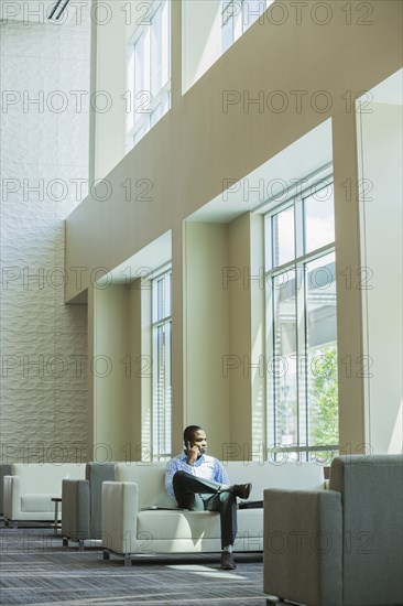 Black businessman talking on cell phone in office lobby