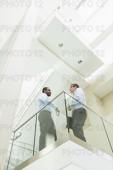 Low angle view of businessmen talking on office balcony