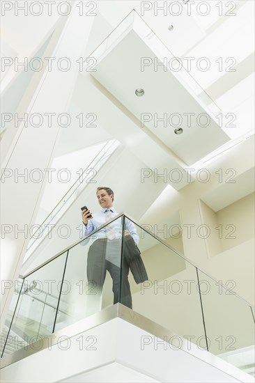 Caucasian businessman using cell phone on office balcony