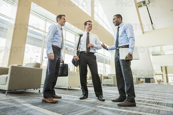 Low angle view of businessmen talking in office lobby