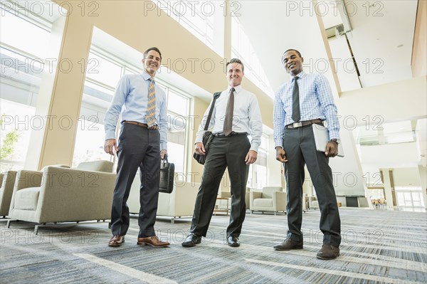 Low angle view of businessmen smiling in office lobby