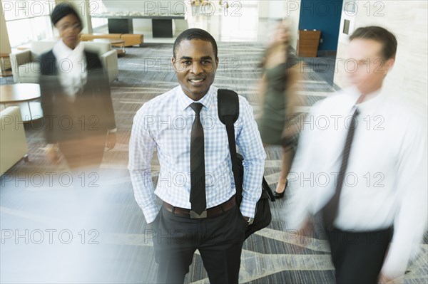 Businessman standing still in busy office lobby