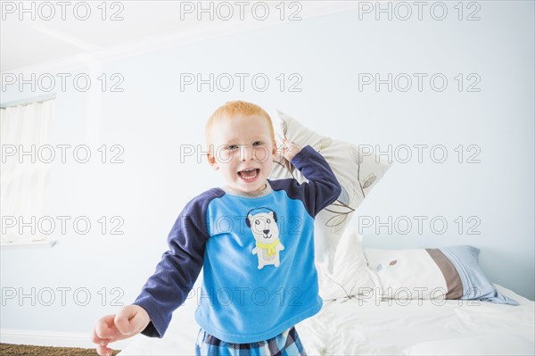 Caucasian boy having pillow fight in bedroom