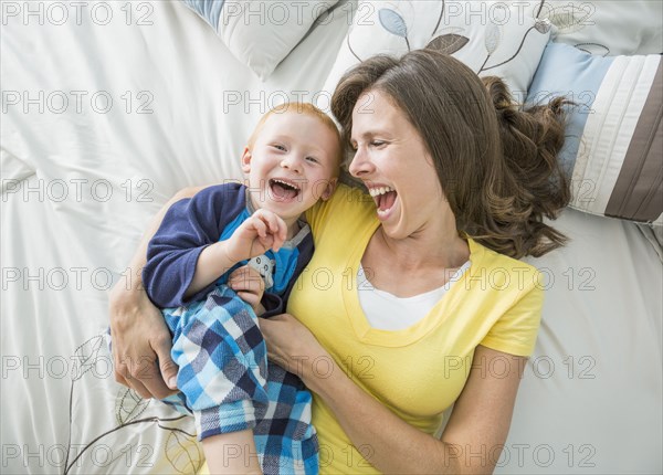 Caucasian mother and son playing on bed