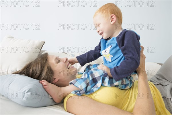 Caucasian mother and son playing on bed