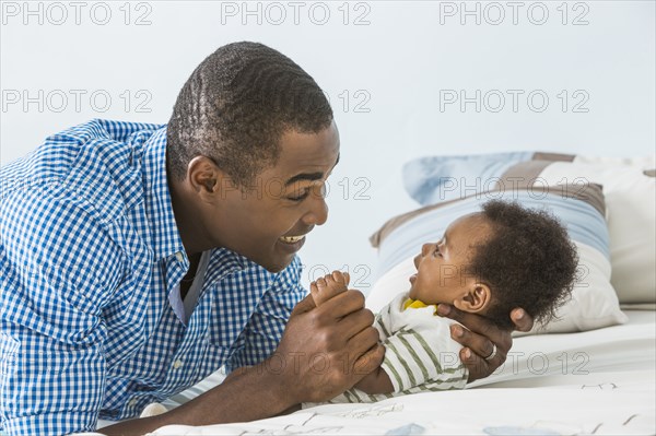 Father cradling baby son on bed