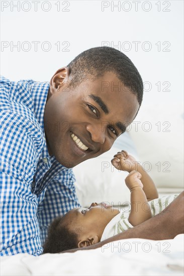 Father smiling with baby son on bed