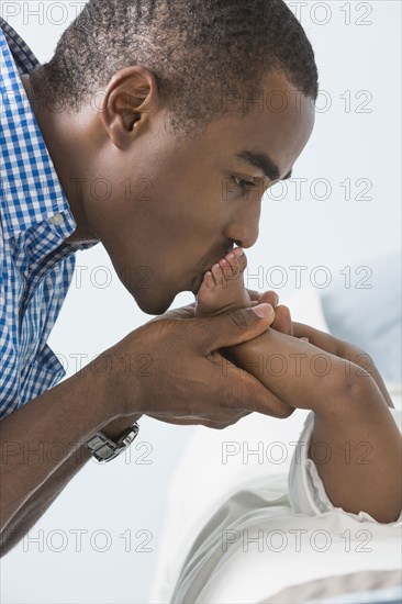 Father kissing feet of baby son