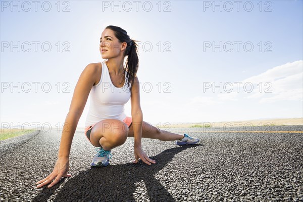 Caucasian runner stretching on remote road