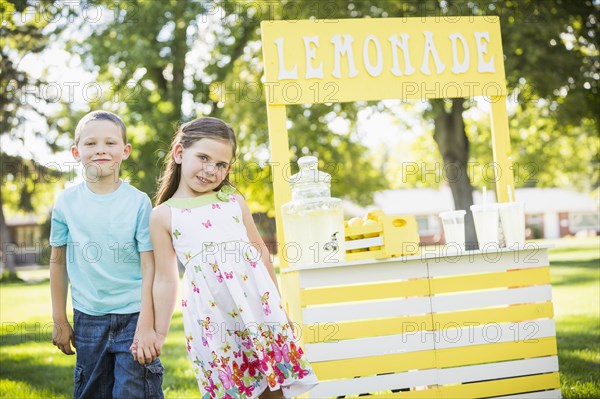 Caucasian brother and sister smiling at lemonade stand