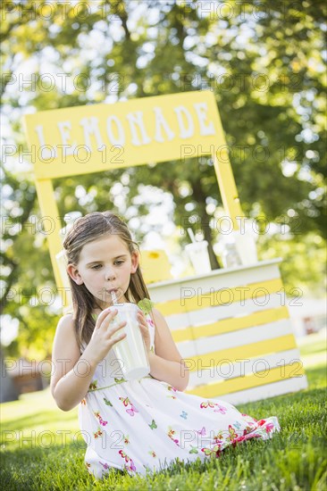 Caucasian girl drinking at lemonade stand