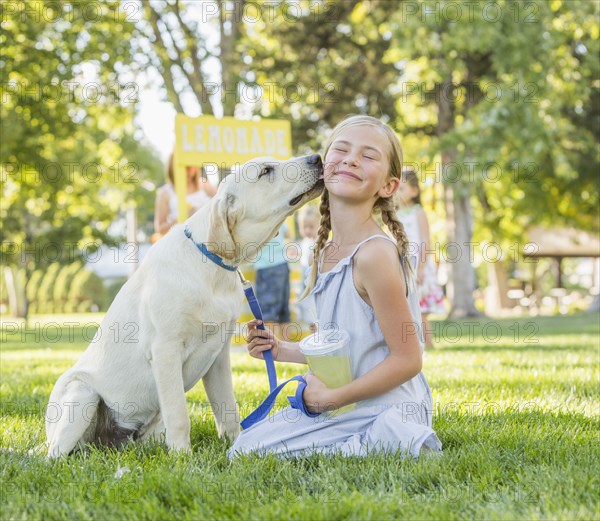 Pet dog licking face of Caucasian girl on grassy lawn