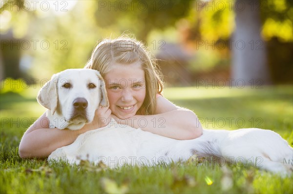 Caucasian girl hugging pet dog on grassy lawn