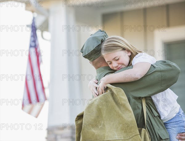 Returning Caucasian soldier hugging daughter