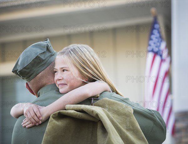 Returning Caucasian soldier hugging daughter