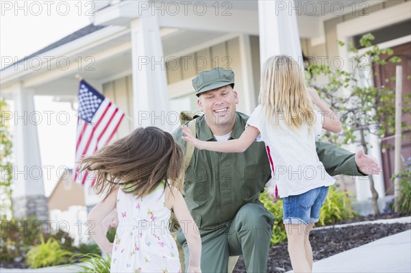 Returning Caucasian soldier hugging daughters