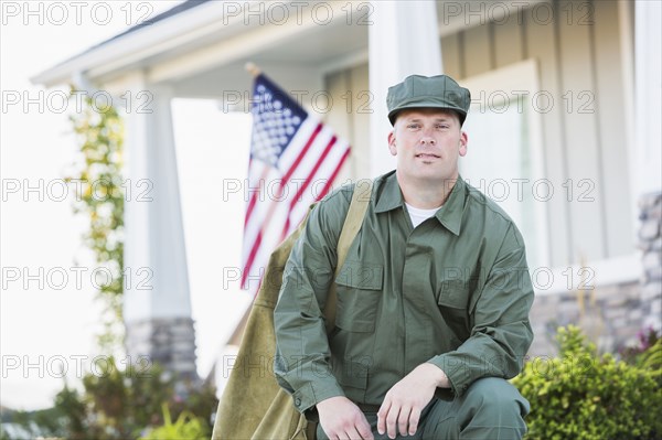 Caucasian soldier kneeling near house